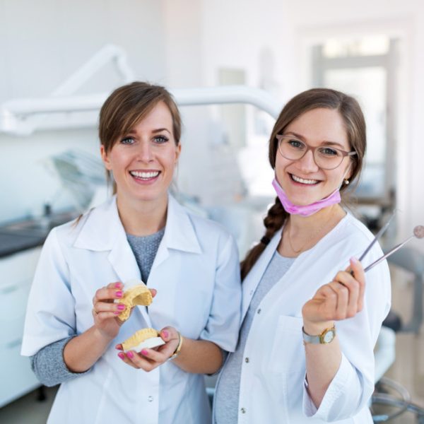two female dentists holding dental equipment in the room